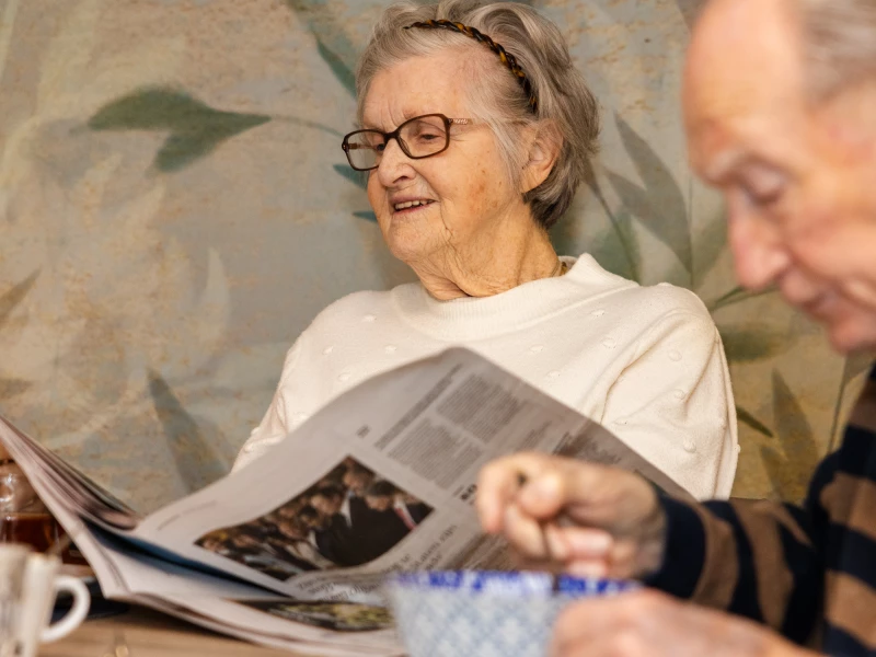 Bewoonster leest de krant samen met een medewerker van Valckenborgh