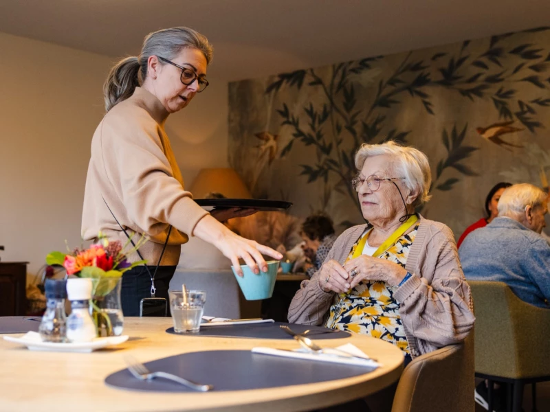 Medewerker schenkt koffie in voor een bewoonster van Valckenborgh