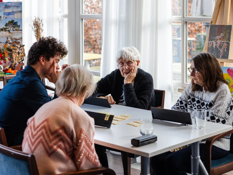 Zorgmedewerkers van Valckenborgh in gesprek met een bewoonster aan tafel