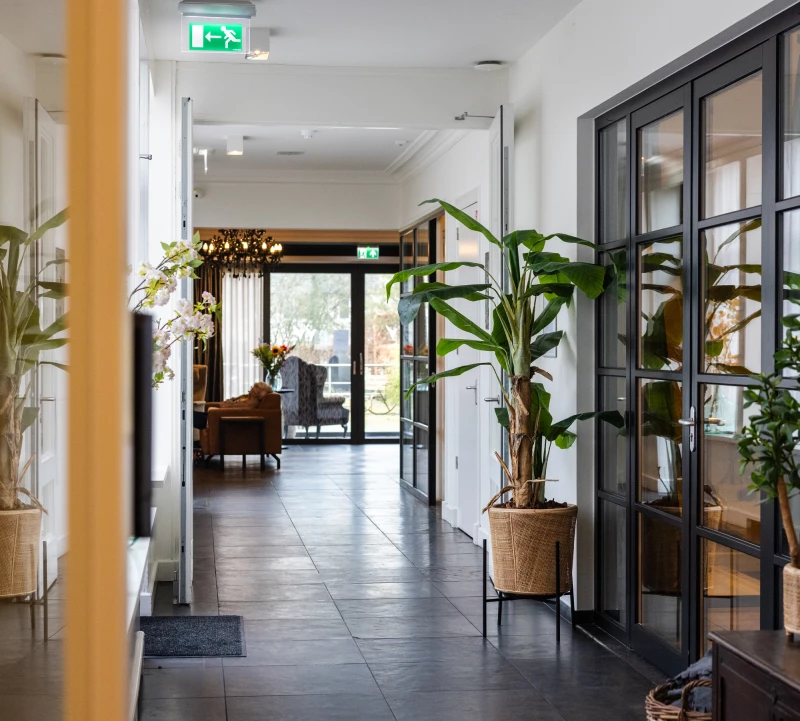Entree met planten en glazen deuren bij Valckenborgh