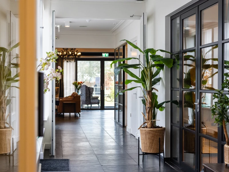 Entree met planten en glazen deuren bij Valckenborgh