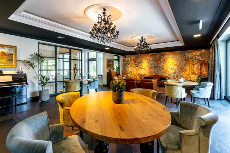 Woonkamer met ronde tafel en zithoeken in zorgvilla Valckenborgh